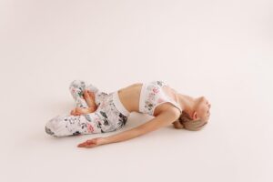 Uma Mulher Em Forma, Vestindo Roupas De Esporte, Realizando Uma Pose De Yoga Elegante Em Um Tapete, Cercada Por Acessórios De Yoga Como Blocos E Uma Faixa.