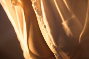 Close-up De Uma Mulher Sedutora Vestindo Uma Camisa Transparente, Iluminada Por Uma Luz Quente, Exibindo Um Tecido Luxuoso Em Um Estilo De Fotografia Erótica.