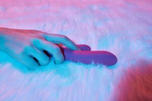Uma Mulher Deitada Em Uma Cama, Segurando Um Vibrador Realista Na Mão, Parecendo Relaxada E Envolvida Em Auto-satisfação.