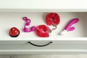 Uma Coleção De Brinquedos Sexuais Modernos Exibidos Em Uma Gaveta De Madeira Aberta, Apresentando Várias Formas E Cores.