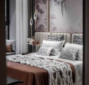Um Quarto Moderno E Luxuoso Com Uma Cama King Size Com Cabeceira Acolchoada, Roupa De Cama Elegante, Mesas De Cabeceira Estilosas Com Lâmpadas E Elementos De Decoração Sofisticados.