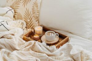 Uma Cena De Quarto Acolhedor Com Lençóis De Seda Luxuosos, Uma Bandeja De Madeira Com Café E Velas, Criando Uma Atmosfera Quente E Convidativa.