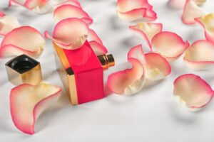 Uma Composição De Uma Garrafa De Perfume Cercada Por Pétalas De Rosa Sobre Um Fundo Claro, Sugerindo Uma Atmosfera Romântica.