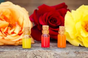 Frascos De óLeos Essenciais Dispostos Com Rosas Frescas, Simbolizando Atração E Perfume.