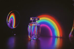 Primeiro Plano De Uma Garrafa De Perfume Com Névoa Iridescente, Diante De Luzes Iluminadas.