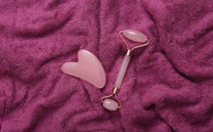 Massajador Facial Discreto Na Cor Rosa, Colocado Sobre Tecido Texturizado.