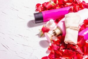 Frascos De Cosméticos Variados Com Pétalas De Rosa Sobre Um Fundo Branco.